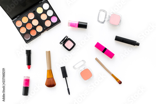 visagiste desk with decorative cosmetics: eyeshadows, lipstick, brush white background top view