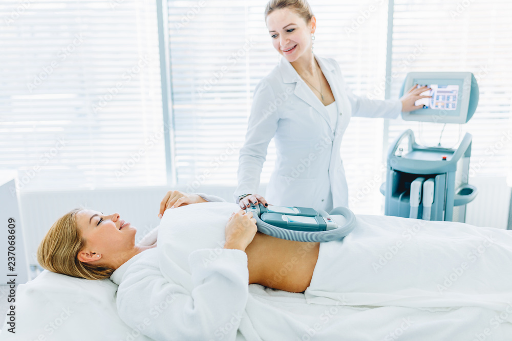 Fototapeta premium Professional caucasian female cosmetologist, Doctor, holding a modern medical hardware equipment for body shape correction, close up, weight loss, body care concept
