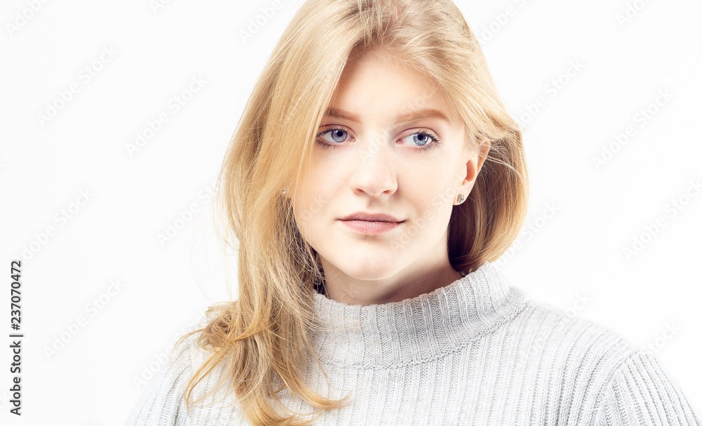 Closeup portrait of a beautiful blonde teenage girl wearing neutral jersey looking to the right isolated on white background Closeup portrait of a beautiful blonde teenage girl wearing neutral jersey looking to the right isolated on white background