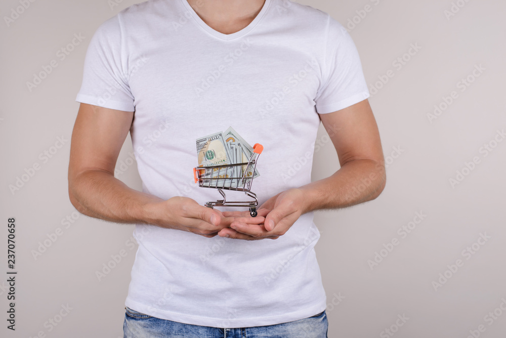Cropped closeup picture photo of small trolley with wheels in hands full of american usa usd paper money isolated on grey background Cropped closeup picture photo of small trolley with wheels in hands full of american usa usd paper money isolated on grey background