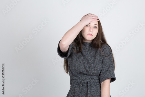 young long-haired woman holding her hand over her head because of misunderstanding