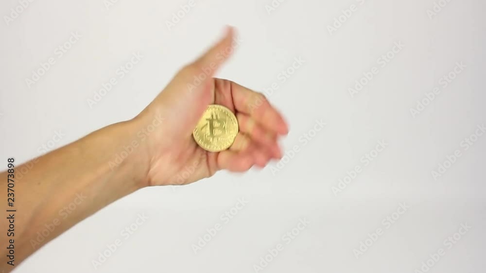 fist with a clamped golden coin of bitcoin appear in the frame, opens the palm and then closes back, white background fist with a clamped golden coin of bitcoin appear in the frame, opens the palm and then closes back, white background