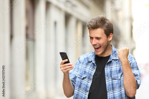 Excited man checking news on phone in the street