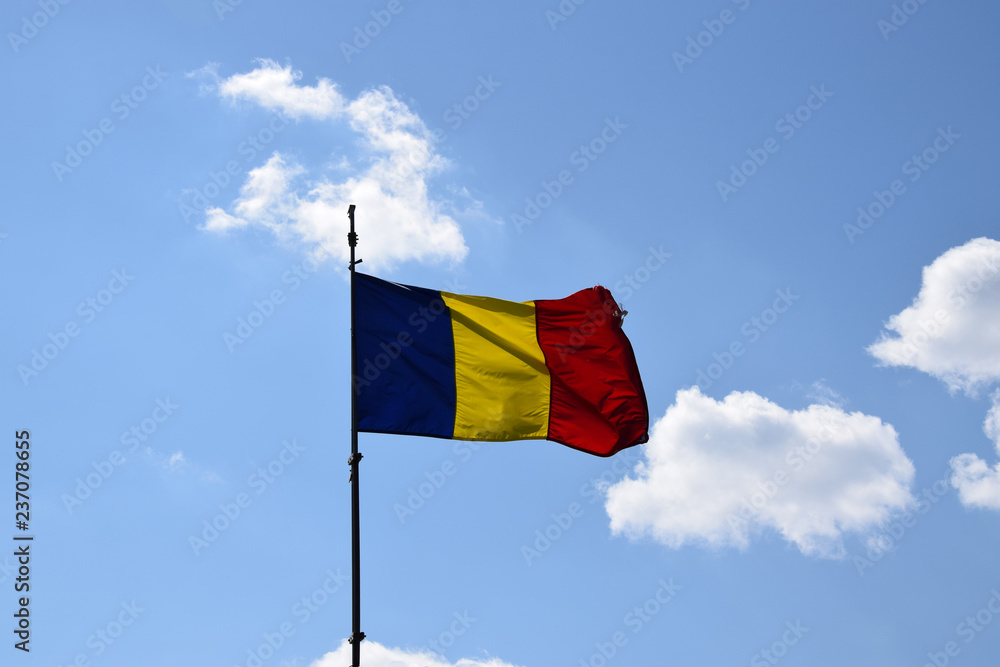 Romanian flag waving in the wind in front of a clean blue sky. Romania National Flag. Romanian flag waving in the wind in front of a clean blue sky. Romania National Flag.