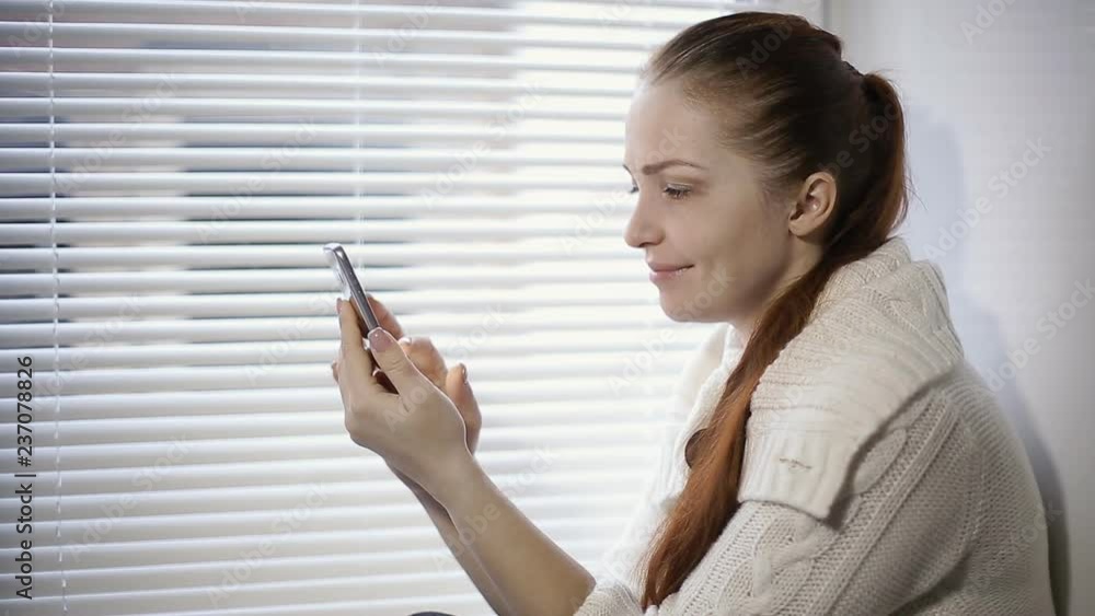 online shopping, a young woman browsing the goods in the online store on the smartphone screen online shopping, a young woman browsing the goods in the online store on the smartphone screen