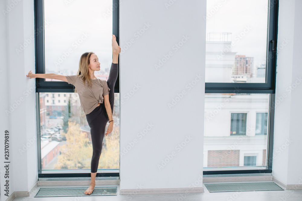 young awesome pleasant sporty girl leaning on the wall while standing on the leg. full length photo. copy space young awesome pleasant sporty girl leaning on the wall while standing on the leg. full length photo. copy space