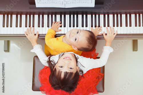 Little asian girl happy to play piano and She taught her brother to play piano.