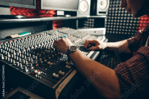 audio enginee fixing the set indoors. close up side view photo, guy working on the technical aspects of sound recording