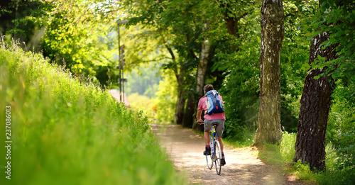 Sportive man cycling in sunny park in hot summer day. Switzerland, Europe