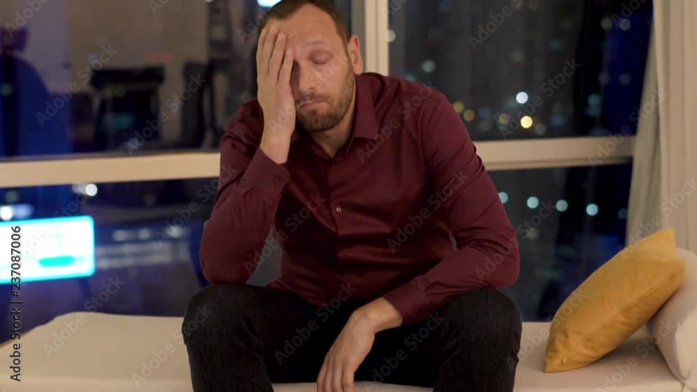 Sad unhappy man sitting on sofa during night
Sad unhappy man sitting on sofa during night
