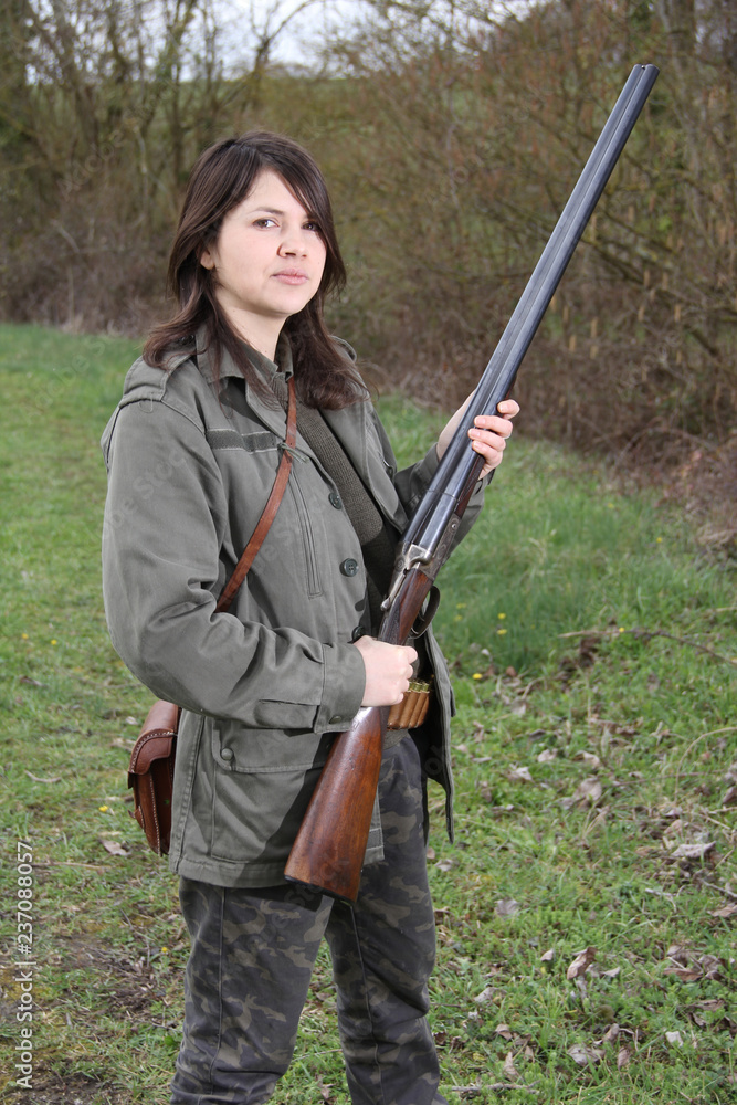 Fototapeta premium Proud woman hunter holding her vintage shotgun in the field