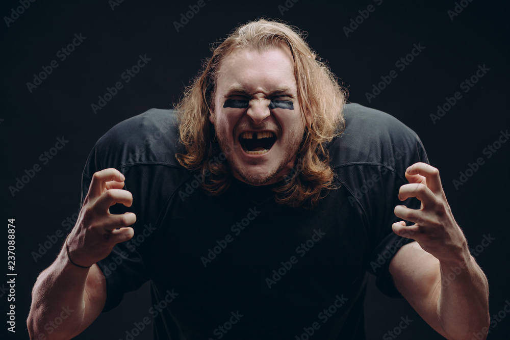 Caucasian football player clenches fists with happiness, being in high