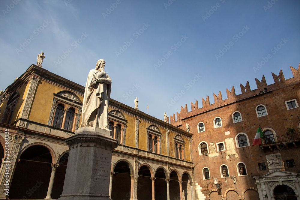Statue of Dante Alighieri in Piazza dei Signori, Verona, Italy. Beautiful statues of Dante in the middle of Verona old town with other sculptures and architecture. Summer day in Verona
