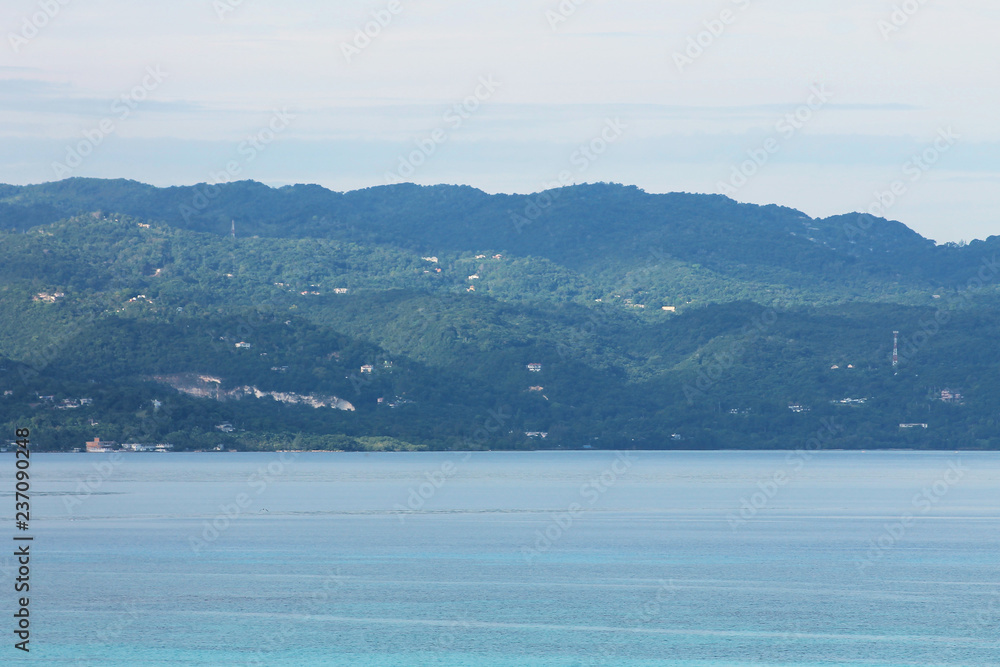 Looking across the bay at the hills, and the hillside house nestled among the trees, Montego Bay, Jamaica.