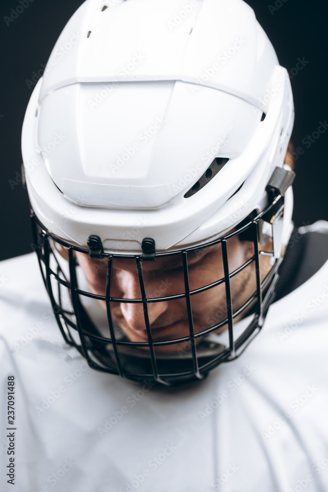 Head portrait of grinning hockey goalie with broken tooth wearing white helmet over black background Head portrait of grinning hockey goalie with broken tooth wearing white helmet over black background
