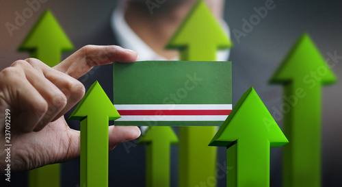 Nation Growth Concept, Green Up Arrows - Businessman Holding Card of Chechen Republic of Ichkeria Flag