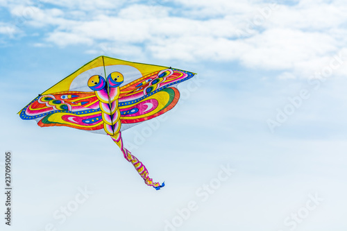 Dragonfly kite flying through blue sky.