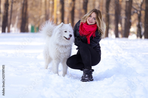 Beautiful young girl with a Samoyed dog in the winter forest on the snow © Alexander