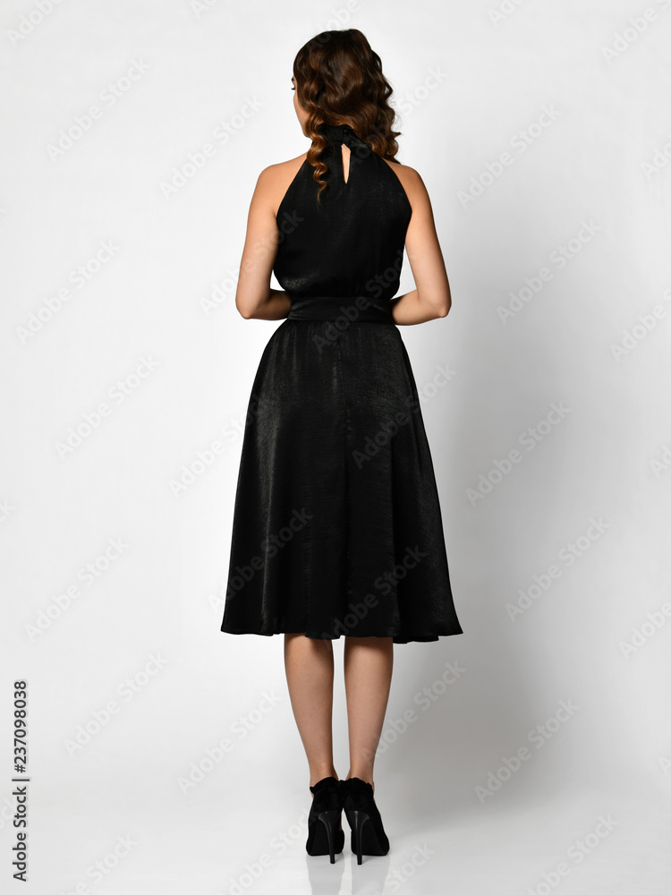 Fototapeta premium Young beautiful woman posing in new dark black fashion winter dress backside rear view