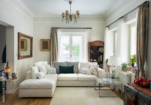 Large living room very bight  with oak wooden floor, four seats sofa, white carpet and retro objets, Greece. © Ruben