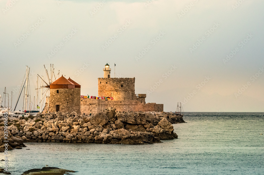 Windmills and the lighthouse at Mandraki Harbour, Rhodes, Greece.