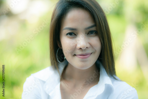 close up face asian younger woman toothy smiling face against green natural background