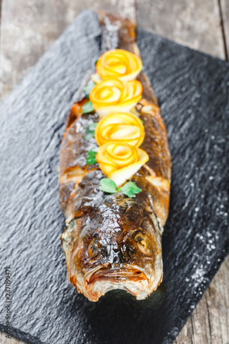 Grilled sea fish with lemon on stone slate background close up. Healthy food. Top view photo