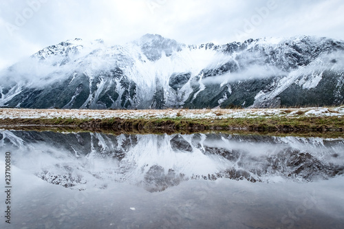 A reflection of the mountain on the water in Mount Cook Village valley covered with white snow after a snowy day.
