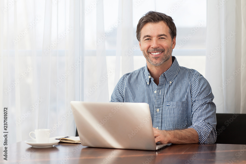 A portrait of a smiling middle-aged bearded man at a desk A portrait of a smiling middle-aged bearded man at a desk