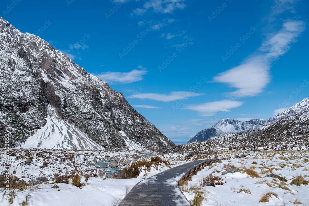 People walking on the boardwalk in Hooker Valley track. Winter snow after a snowy day scene. Mount Cook National Park.