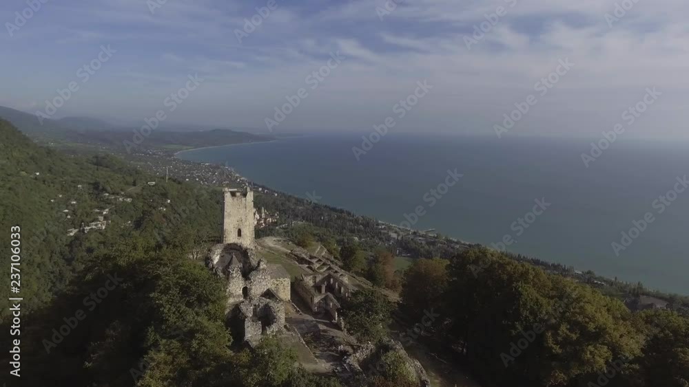 Drone shows aerial view of beautiful Anacopia Fortress in Abkhazia and amazing Black Sea with long shore coast connecting with valley and green hills on summer sunny day with amazing blue sky. Drone shows aerial view of beautiful Anacopia Fortress in Abkhazia and amazing Black Sea with long shore coast connecting with valley and green hills on summer sunny day with amazing blue sky.
