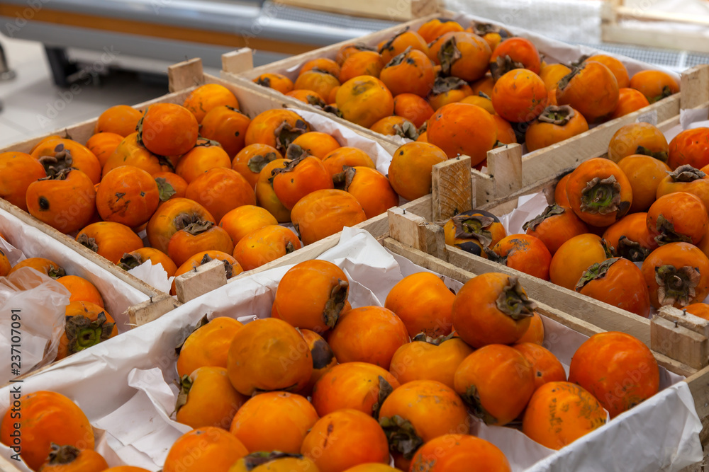 A large rack with wooden baskets with persimmons in the fruit department of the shopping center. Fresh and healthy foods for every day diet.