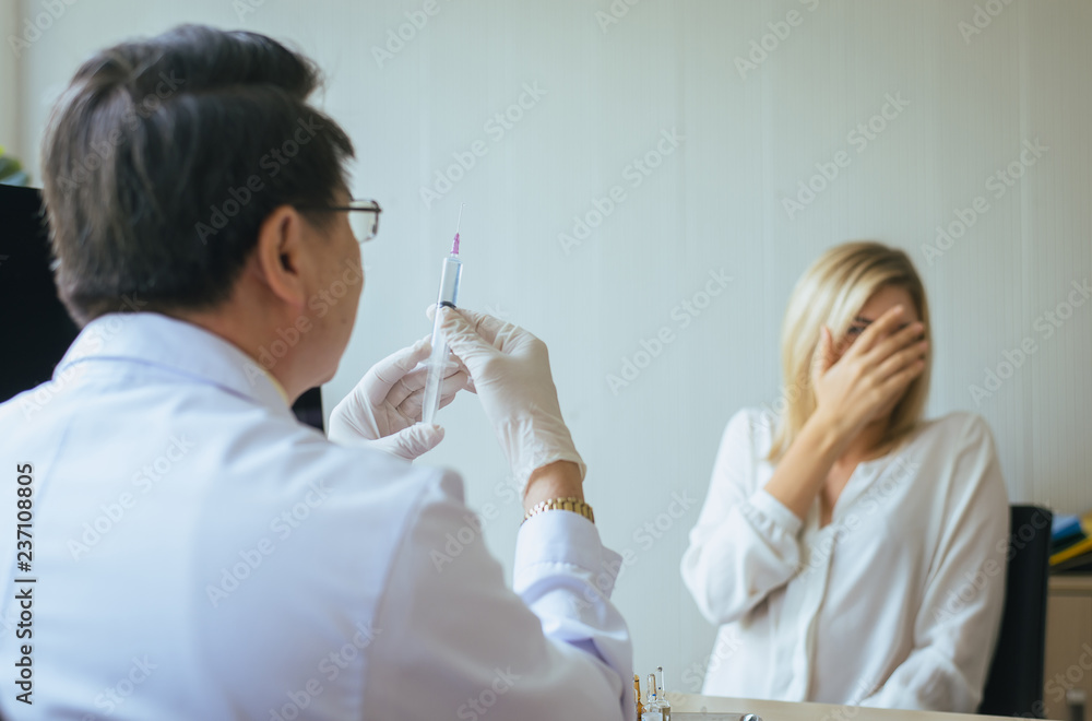 Doctor preparing the medicine or giving vaccine to woman patient with injection or syringe in hospital room Doctor preparing the medicine or giving vaccine to woman patient with injection or syringe in hospital room