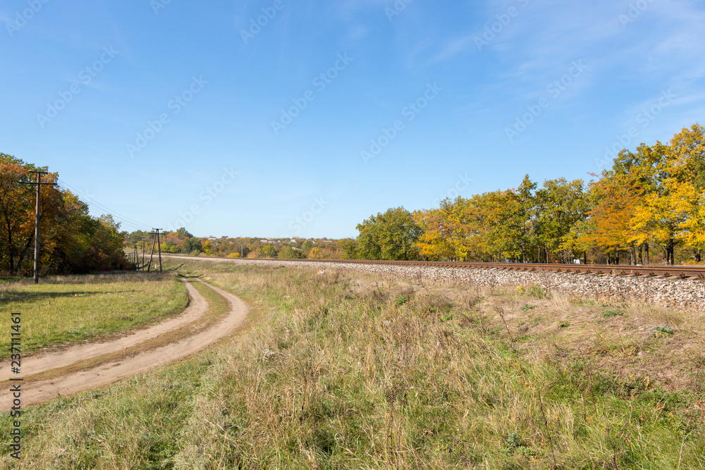 Autumn landscape with railway and country road
