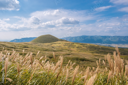 Komezuka volcano in Aso, Kumamoto, Kyushu, Japan, green grass field cover the mountain with blue sky and cloud background