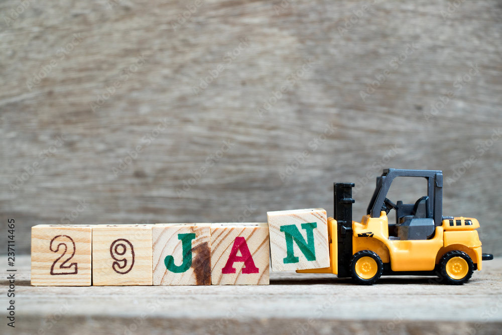 Obraz premium Toy forklift hold block N to complete word 29jan on wood background (Concept for calendar date in 29 month January)