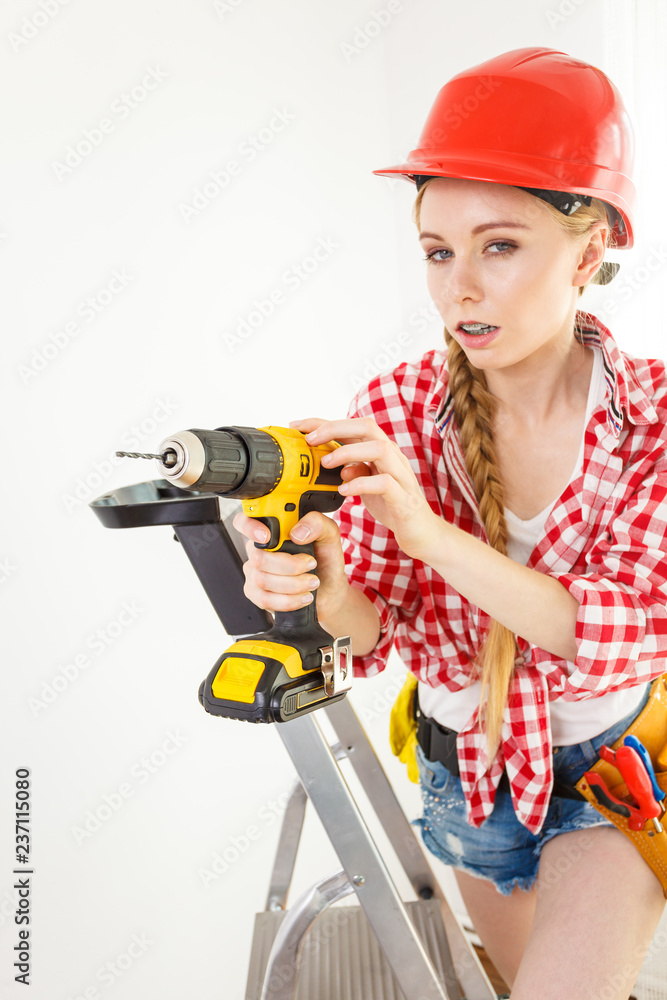 Woman using drill on ladder Woman using drill on ladder