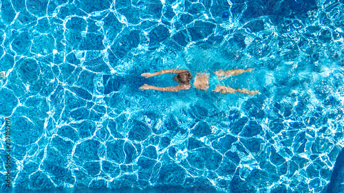 Active girl in swimming pool aerial drone view from above  young woman swims in blue water  tropical vacation  holiday on resort concept  