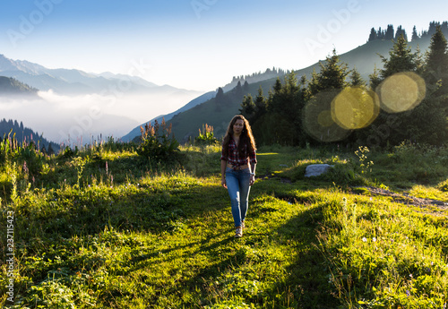 woman traveler with backpack holding hat and looking at amazing mountains and forest  wanderlust travel concept  space for text  atmosperic epic moment