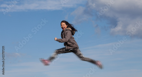 Cute girl running jumping at the on a field in the summer