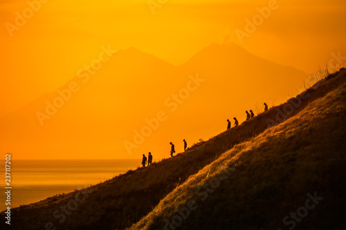 Tourists hiking down a hill at sunset, Komodo Island, Indonesia photo