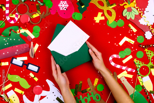 Christmas party props: blank space paper letter, champagne, sweet canes, Santa's HoHoHo, glass of champagne and pine tree glasses isolated on red background. Merry Christmas and Happy 2019 New Year.