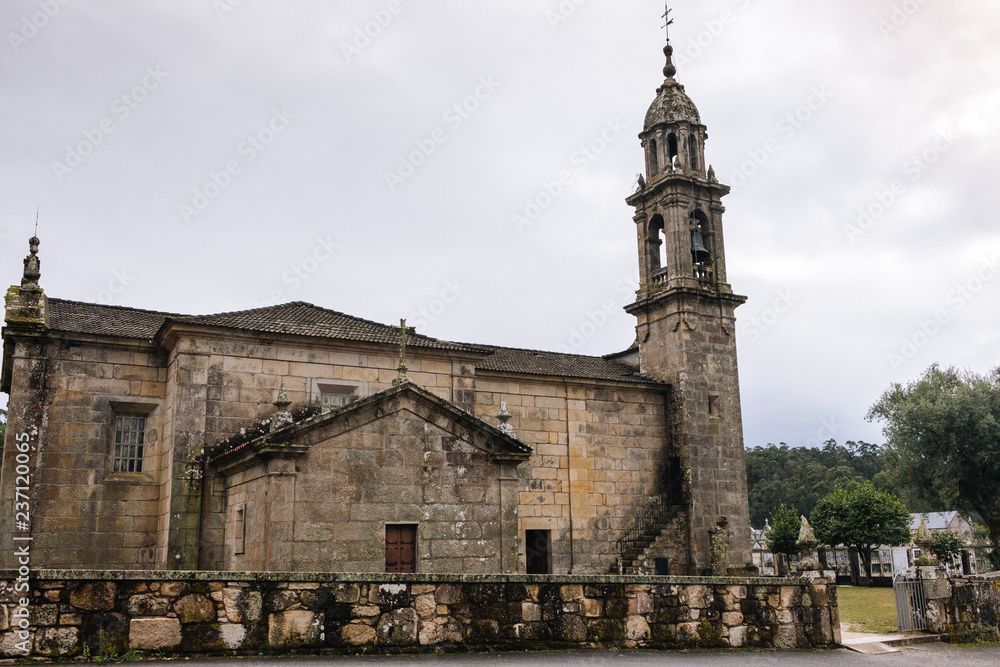 Ancient stone church with tower and cemetery. Medieval monastery landmark. Mystical exterior of catholic catherdal. Old temple with cross. Faith and religion concept. Religious architecture.
