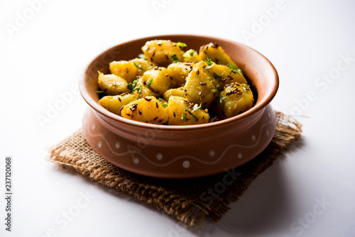 Jeera Aloo is a Indian main course dish which goes well with hot puris, chapatti, roti or dal. served in a bowl over moody background. selective focus photo