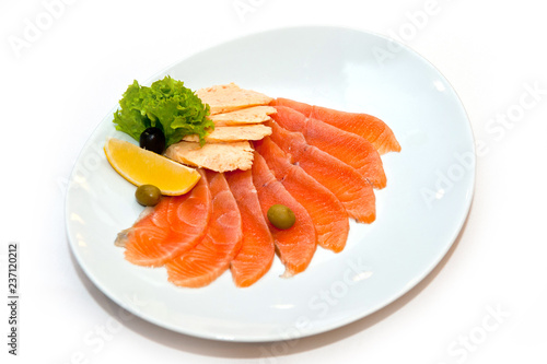 Cutting red fish with an orange slice in greens and olives