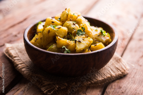 Jeera Aloo is a Indian main course dish which goes well with hot puris, chapatti, roti or dal. served in a bowl over moody background. selective focus