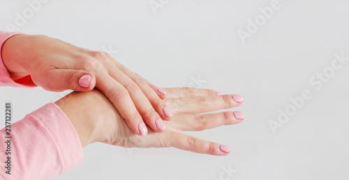 Beautiful delicate women's hands with pink manicure smudge caring cream hand massage isolated on gray background close up, banner