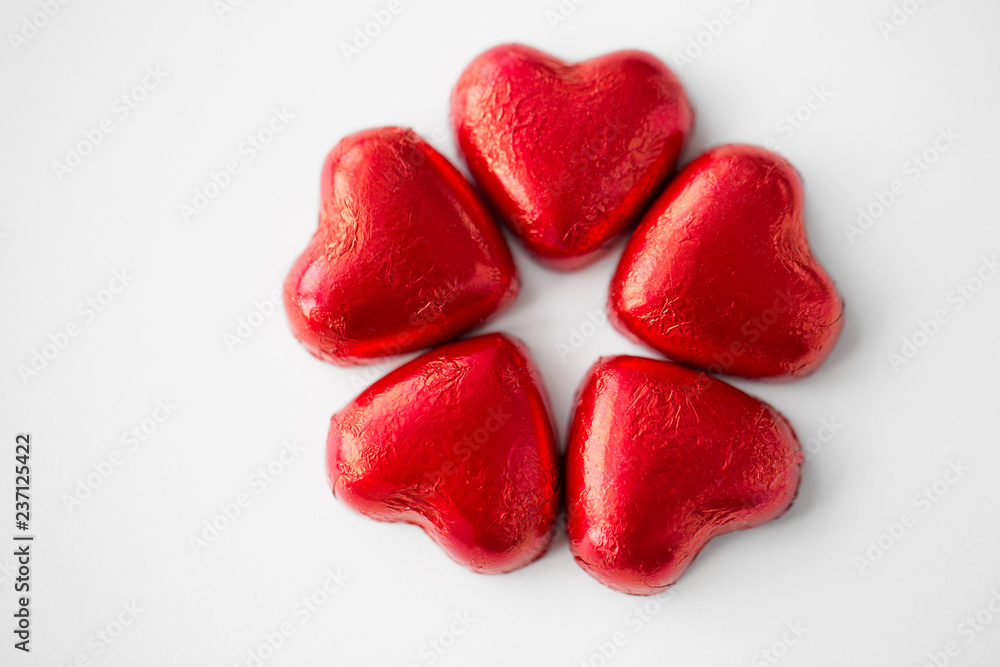 valentines day, sweets and confectionery concept - close up of red heart shaped chocolate candies on white background