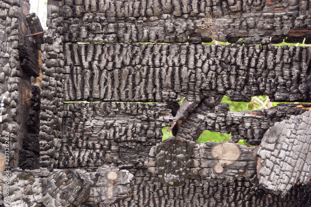 Black burnt wall of house of wooden planks with embossed texture. background for copy space. concept of loss of real estate or home. property insurance