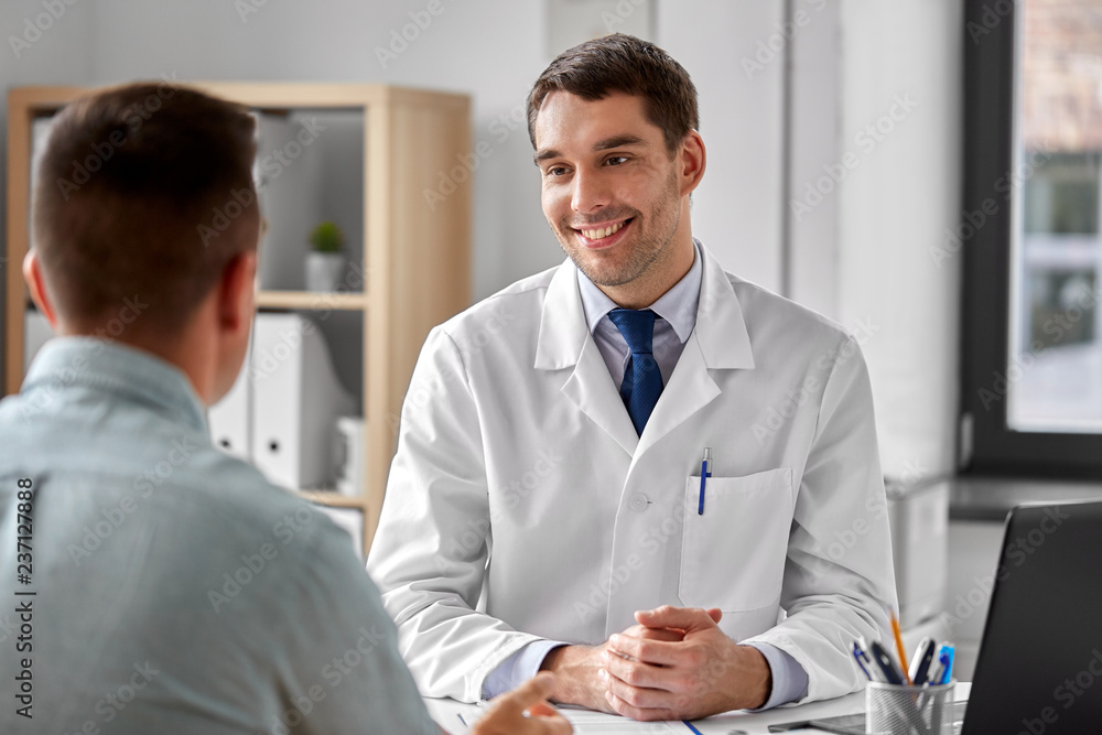 medicine, healthcare and people concept - smiling doctor talking to male patient at medical office in hospital medicine, healthcare and people concept - smiling doctor talking to male patient at medical office in hospital